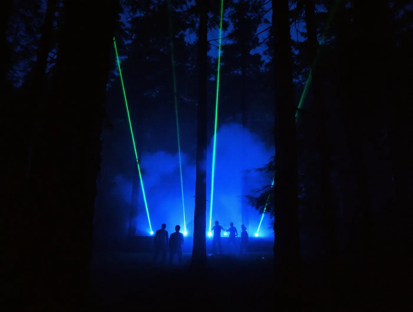 Leśna scena techno, zielone lasery w mgle między sosnami